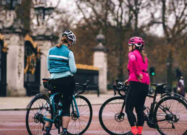Two women holding their bicycles and engaged in conversation