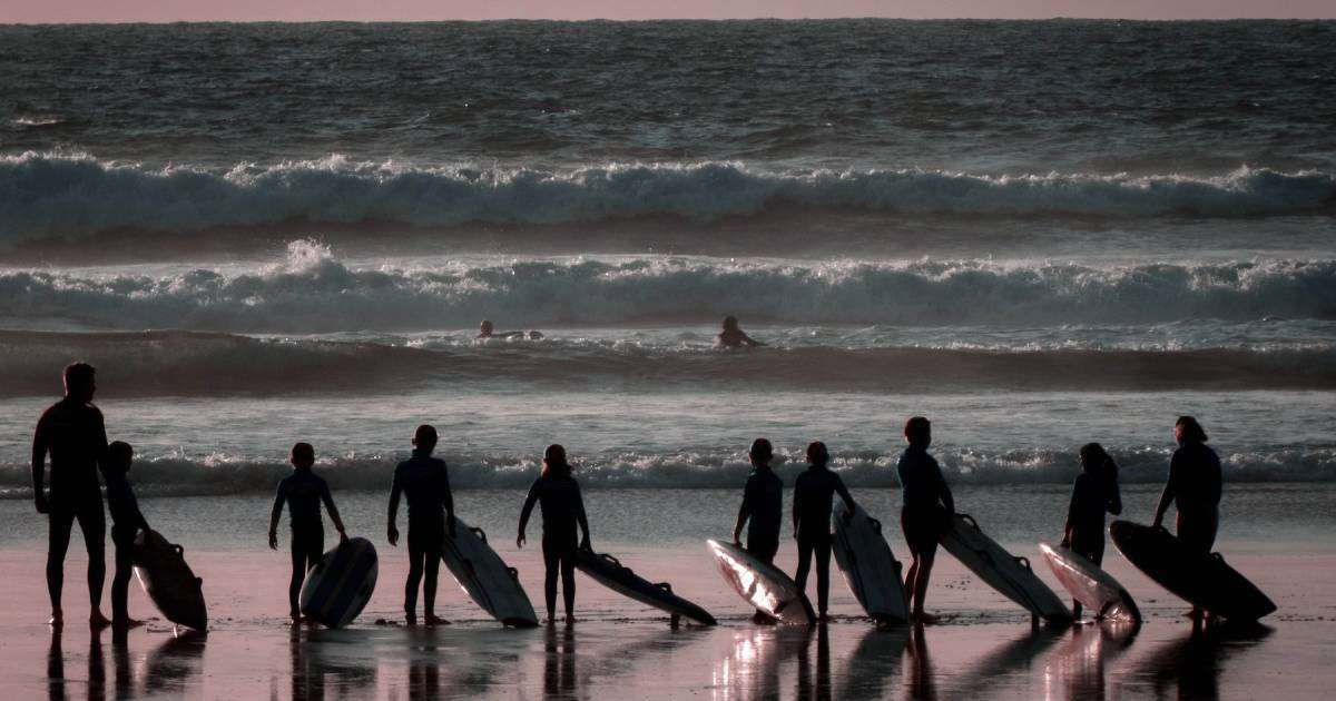 A group of people standing with a surfboard in Cornwall.