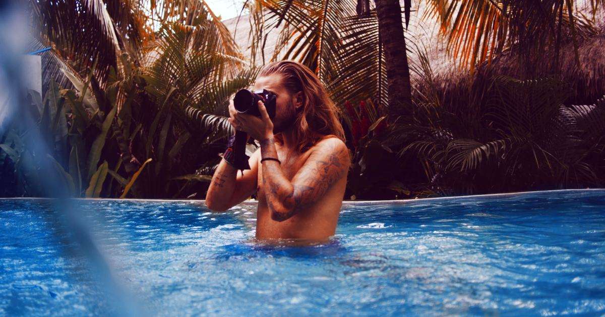 A man in a pool is clicking pictures with a camera.