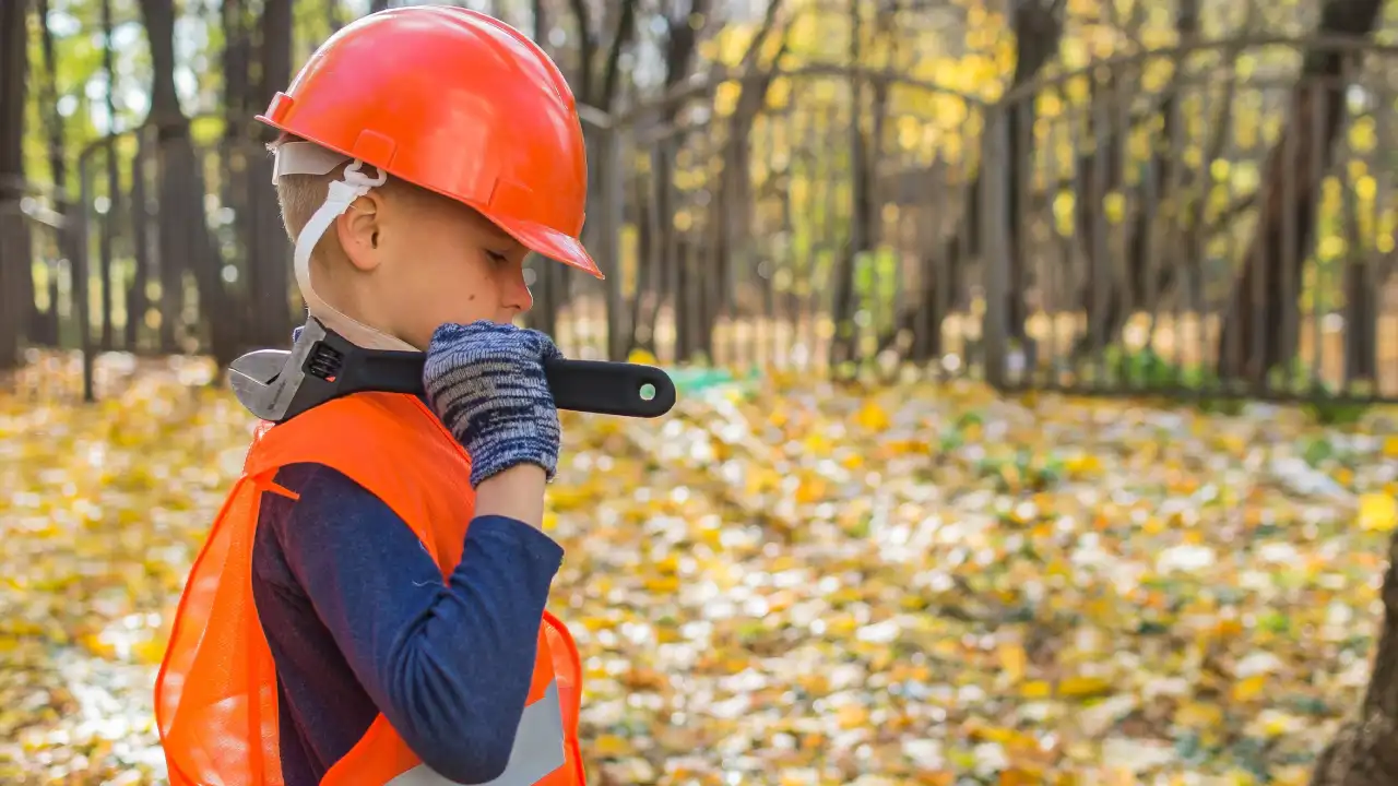 a boy dressed as a working man in a hard hat with a wrench
