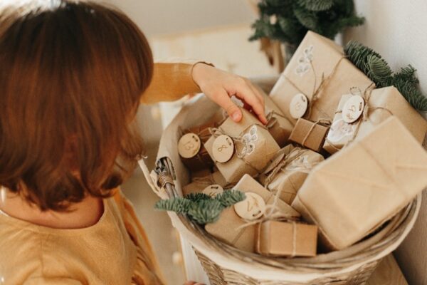 A woman is holding a bucket of wrapped gifts.